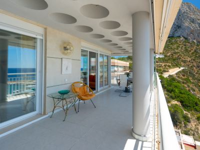 Große überdachte Terrasse mit Panoramablick auf das Meer und den majestätischen Peñón de Ifach. Mit markanter runder Deckengestaltung, Fliesenboden und Glasschiebetüren zum Innenbereich.
