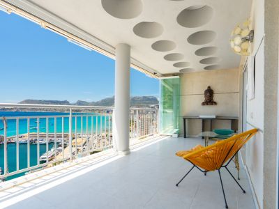 Großzügige überdachte Terrasse mit markanter runder Deckengestaltung und Glasvorhängen, mit Panoramablick auf Calpes Hafen, das türkisfarbene Meer und die Berge.