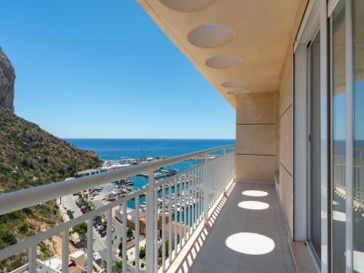Helle Privatterrasse mit Fliesenboden, weißem Geländer und runden Deckenausschnitten. Bietet direkten Blick auf den Yachthafen, das Meer und den Peñón de Ifach.