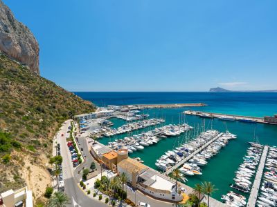 Panoramablick auf den belebten Yachthafen von Calpe, eingerahmt vom majestätischen Peñón de Ifach und dem klaren türkisfarbenen Mittelmeerwasser.