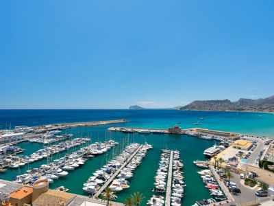 Panoramablick auf den Yachthafen von Calpe mit zahlreichen Booten im türkisfarbenen Wasser und der Mittelmeerküste bis zum Peñón de Ifach.