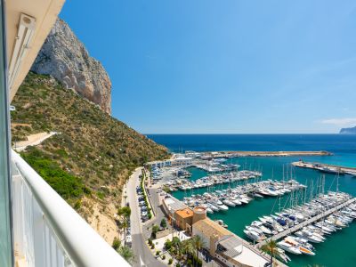 Panoramablick von der Terrasse auf den majestätischen Peñón de Ifach, den belebten Yachthafen von Calpe mit seinen Booten und das tiefblaue Mittelmeer.