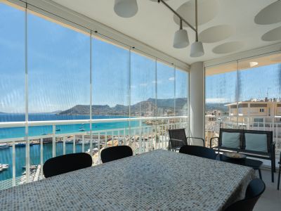 Verglaste Terrasse mit Essbereich, direkter Blick auf Calpes Yachthafen, das türkisfarbene Meer und den ikonischen Peñón de Ifach.