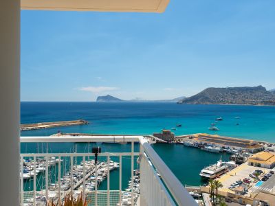 Weitläufiger Meer- und Hafenblick vom Balkon mit zahlreichen Booten, der türkisfarbenen Bucht und fernen Bergen unter klarem blauem Himmel.