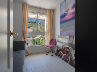 Zusätzliches Schlafzimmer oder Arbeitszimmer mit Bergblick, ausgestattet mit Sofa, Bürostuhl und hellem Fliesenboden. Dekoriert mit maritimer Kunst und einem dunklen Kleiderschrank.