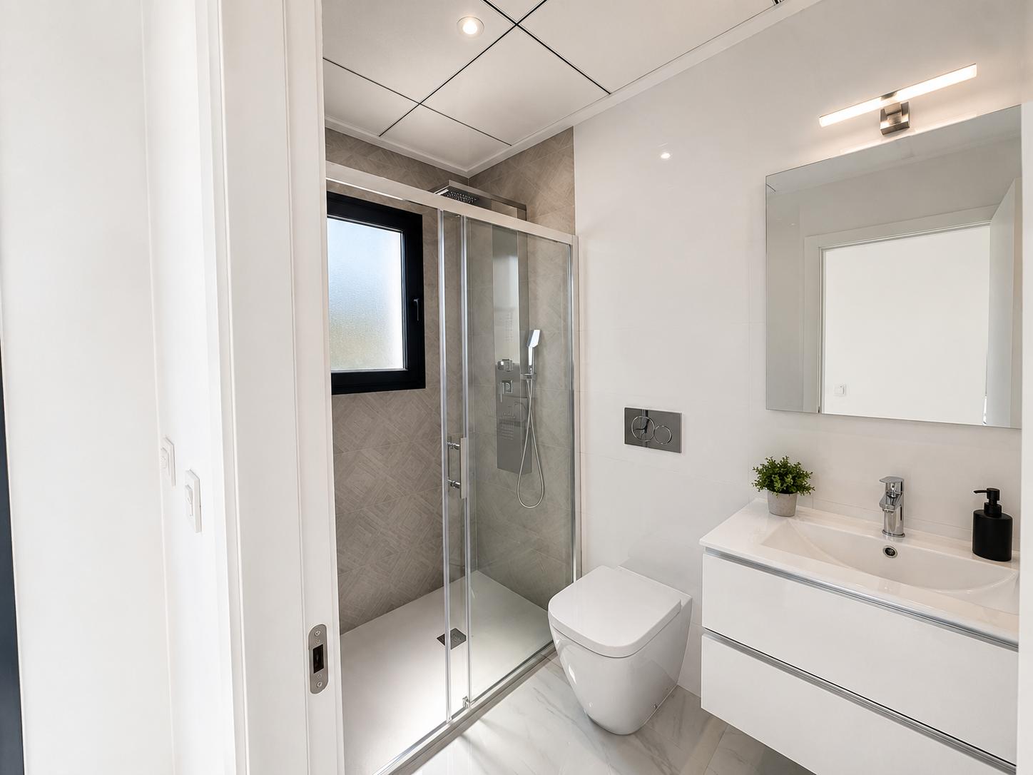 Modernes Bad mit schwebendem weißen Waschtisch, wandhängendem WC und begehbarer Dusche mit grauen Strukturfliesen und Milchglasfenster. Marmorierte Bodenfliesen.