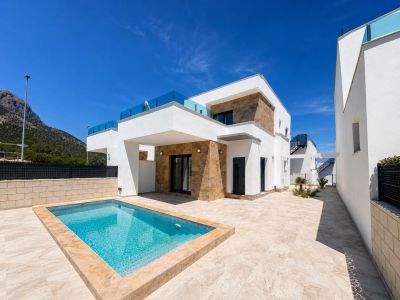 Der Außenbereich der modernen Villa zeigt einen rechteckigen Privatpool und eine helle Fliesenterrasse. Weiße Fassaden mit Natursteinakzenten und Glasbalustraden rahmen den Bergblick ein.