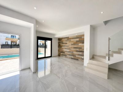 Geräumiger Wohnbereich mit polierten Porzellanfliesen, dekorativer Wandverkleidung in Holzoptik und direktem Zugang zum privaten Pool. Moderne Treppe mit Glasgeländer.