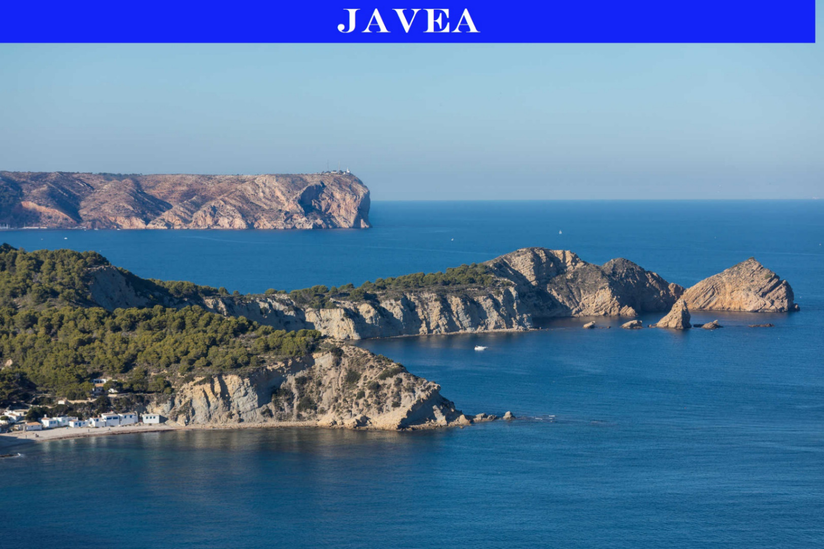 Panoramablick auf Jáveas zerklüftete Küste, mit pinienbewachsenen Klippen, einer abgelegenen Bucht mit weißen Häusern und felsigen Inseln im blauen Mittelmeer, sowie einem entfernten Leuchtturm.