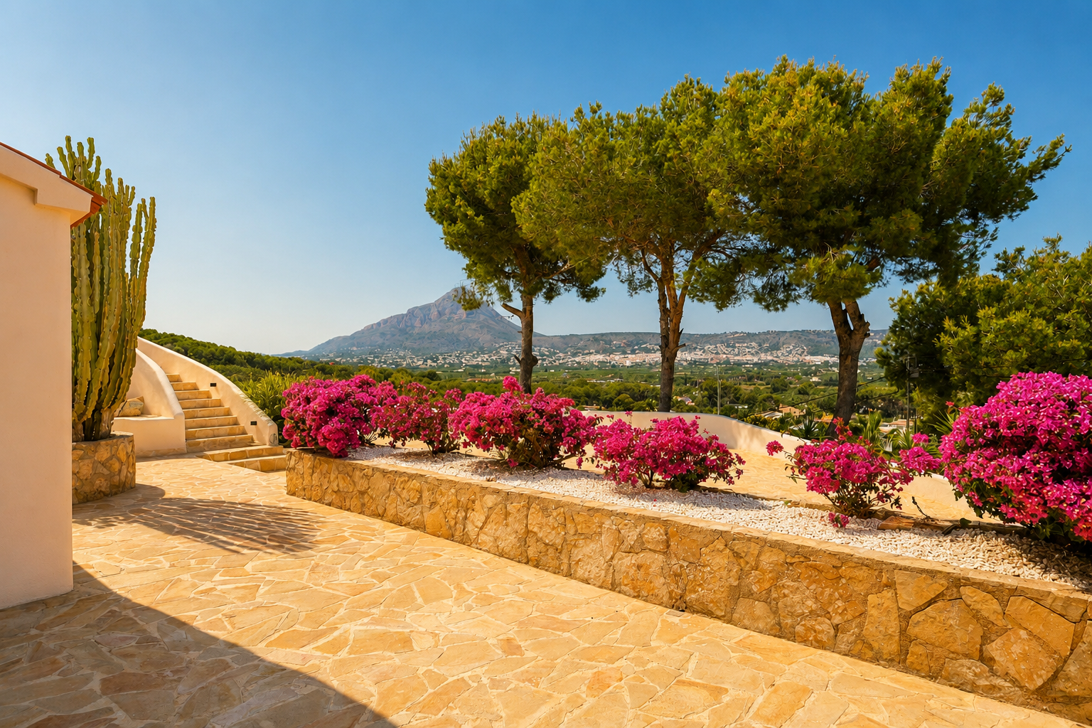 Außenterrasse mit Natursteinpflaster, geschwungener Treppe und leuchtenden Bougainvilleen. Ein großer Kaktus und Panoramablick auf Berge und die Stadt.