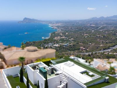 Luftaufnahme der Dachterrasse der Villa mit weißer Wendeltreppe, Kunstrasen, Glasgeländer und weitem Blick auf das Mittelmeer und die Küstenlandschaft.