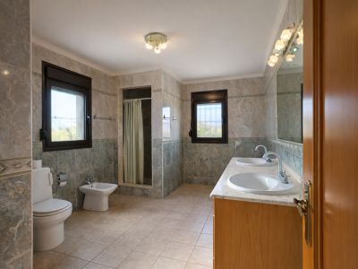 Geräumiges Badezimmer mit Doppelwaschtisch auf Marmorplatte und Holzunterschrank. Ausgestattet mit ebenerdiger Dusche, WC, Bidet und zwei Fenstern für Tageslicht.