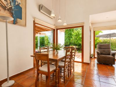 Helles Hauptwohnzimmer mit handgefertigten Terrakottaböden, einem markanten doppelseitigen Kamin und großen Fenstern, die den Raum mit natürlichem Licht und mediterranem Flair erfüllen.