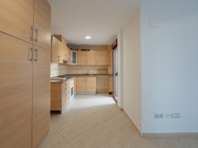 Ausgestattete Küche mit hellen Holzschränken, Granitarbeitsplatten und Fliesenboden. Eine Glastür führt zu einem Patio.