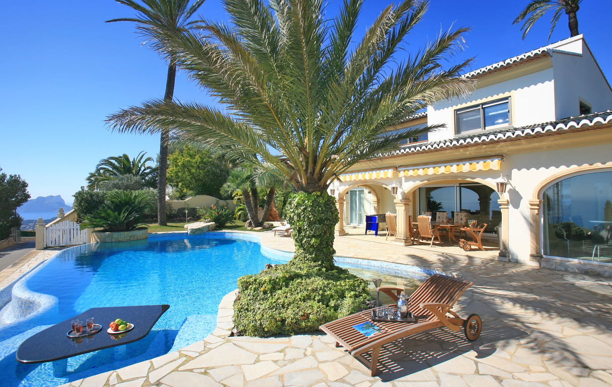 Der einzigartig gestaltete Pool bietet einen integrierten Tisch für Getränke, umgeben von einer Steinterrasse und Palmen, mit Fernblick auf das Meer.