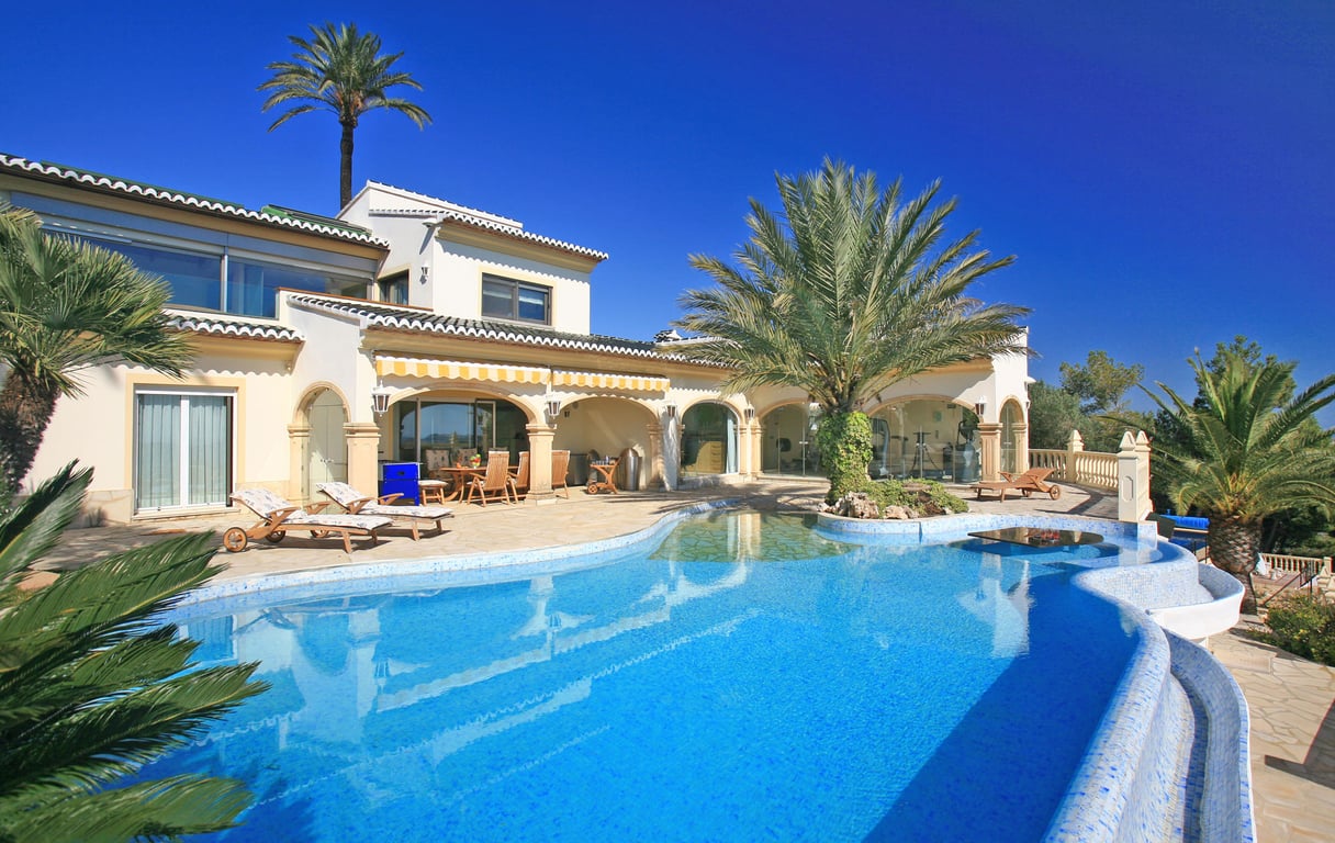 Großer blauer Mosaikpool mit Strandzugang, Palmeninsel und Wassertisch. Die Villa verfügt über eine überdachte Naya und einen verglasten Fitnessraum.