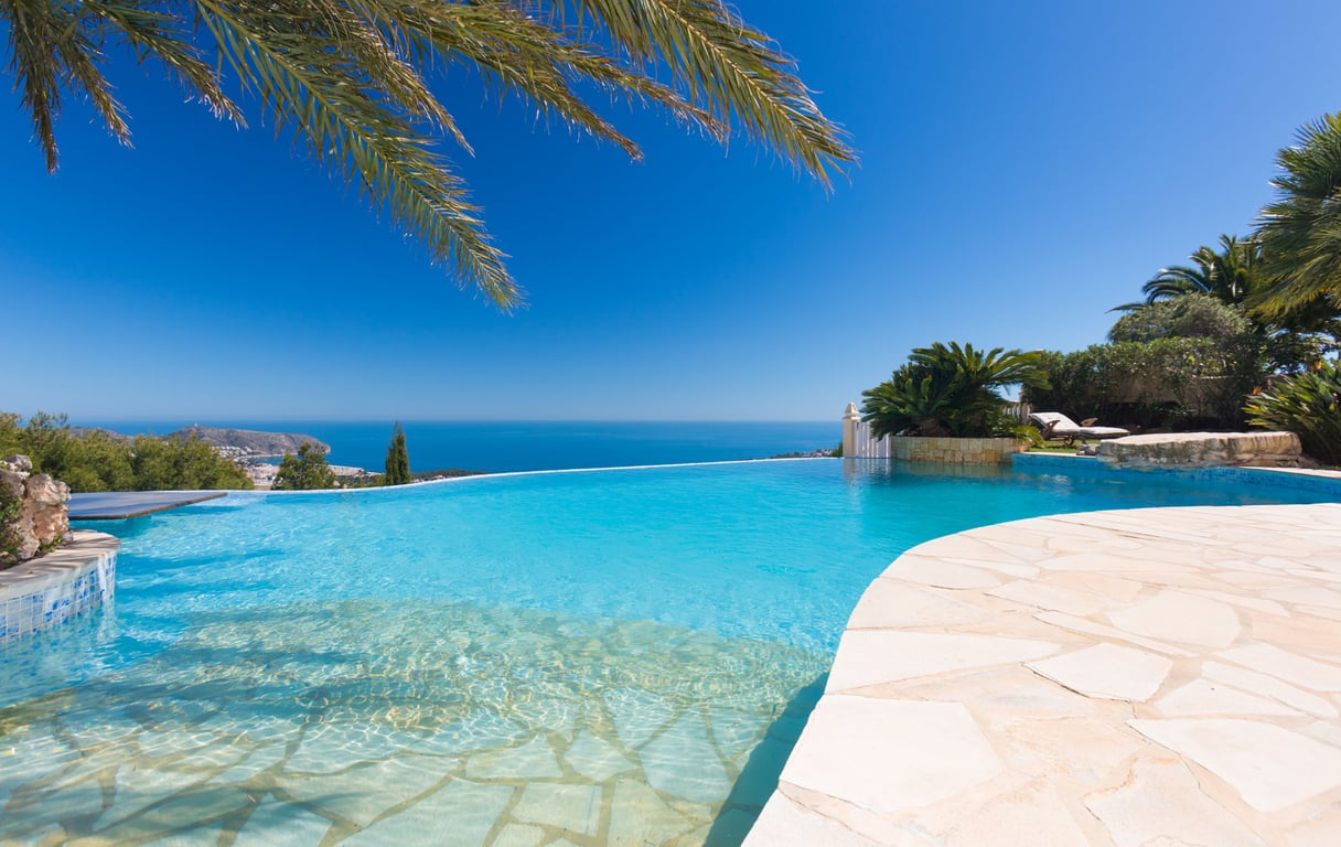 Infinity-Pool mit flachem Einstieg und hellem Steinrand, der einen weiten Blick auf das Mittelmeer und die Küste bietet.