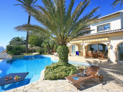 Der einzigartig gestaltete Pool bietet einen integrierten Tisch für Getränke, umgeben von einer Steinterrasse und Palmen, mit Fernblick auf das Meer.