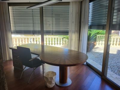 Geräumiges privates Büro mit großem Holzschreibtisch und Parkettboden. Die bodentiefen Fenster blicken auf eine Balustrade und einen mediterranen Garten.