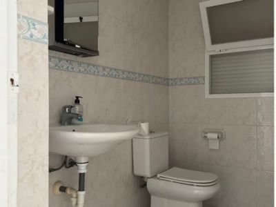 Funktionales Badezimmer mit hellen Wandfliesen und dekorativer Bordüre. Ausgestattet mit Wandwaschbecken, Toilette und beleuchtetem Spiegel, ergänzt durch ein Kippfenster.