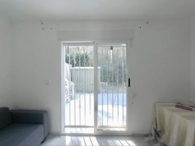 Geräumiger Raum mit Glasschiebetüren und Sicherheitsgittern, direktem Zugang zum privaten Garten und viel Tageslicht auf dem hellen Boden.