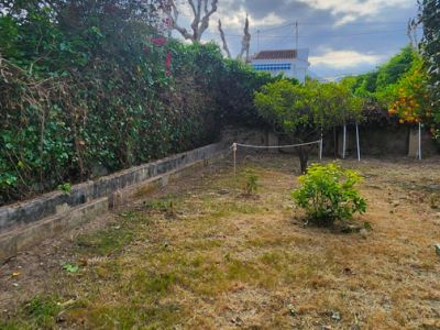 Hinterer Garten mit offenem Gelände, Obstbäumen und blühender Hecke. Im Vordergrund eine Holzbasis mit Kunstrasen. Ideal zur Personalisierung und für einen Pool.
