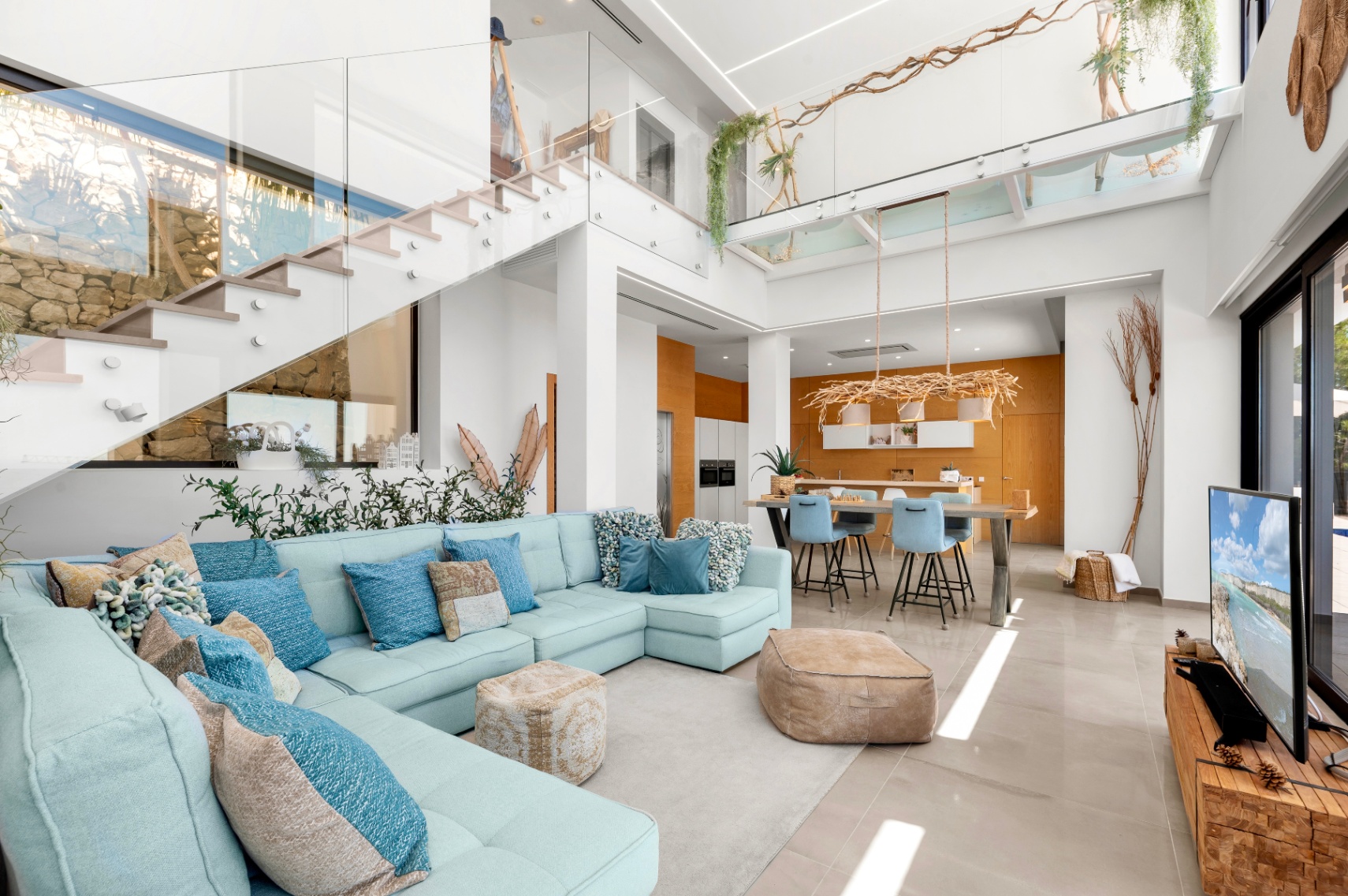 Großzügiger offener Wohnbereich mit hellblauem Ecksofa, moderner Glasgeländer-Treppe und Küche mit warmen Holzdetails, alles durchflutet von Tageslicht. Großzügiger offener Wohnbereich mit hellblauem Ecksofa, moderner Glasgeländer-Treppe und Küche mit warmen Holzdetails, alles durchflutet von Tageslicht.