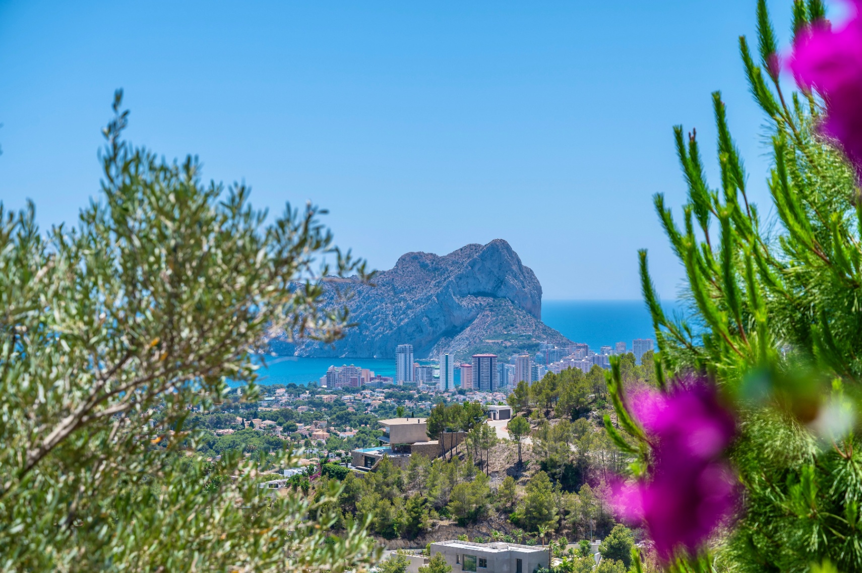Panoramablick auf den Peñón de Ifach und die Küste von Calpe, umrahmt von mediterraner Vegetation, mit modernen Villen am Hang. Panoramablick auf den Peñón de Ifach und die Küste von Calpe, umrahmt von mediterraner Vegetation, mit modernen Villen am Hang.