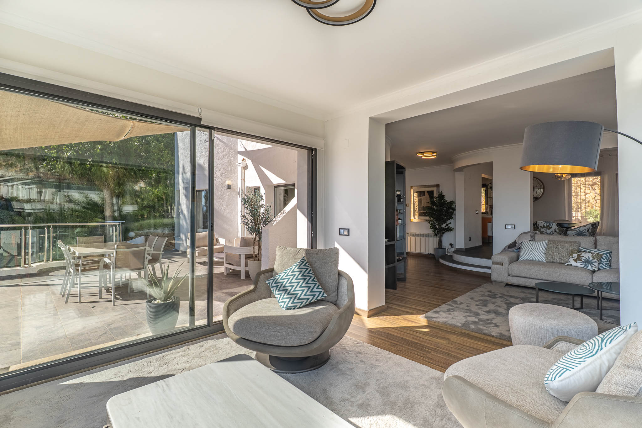 Modernes Wohnzimmer mit großen Glastüren, die sich nahtlos zur Terrasse öffnen und einen atemberaubenden Panoramablick auf das Mittelmeer sowie reichlich Tageslicht bieten.