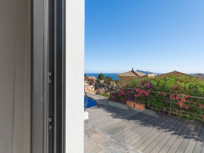 Blick von der Schiebetür auf die Terrasse mit WPC-Dielen, Poolausschnitt und Edelstahlgeländer. Im Hintergrund sind das Mittelmeer und traditionelle Dächer zu sehen.