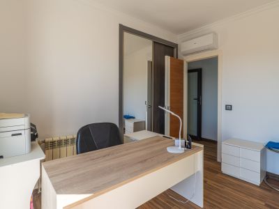 Helles Arbeitszimmer mit hellem Holzschreibtisch, Laminatboden, verspiegeltem Schiebetürenschrank und Klimaanlage.