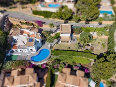Luftaufnahme der Villa mit unregelmäßig geformtem Pool, weitläufigen flachen Gärten mit Teich und einem separaten Nebengebäude. Traditionelle Ziegeldächer und mediterrane Vegetation prägen das Bild.