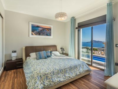 Schlafzimmer mit Doppelbett, Holzlaminatboden und weitem Meerblick durch die große Glasschiebetür. Ein Spiegelschrank ist ebenfalls vorhanden.
