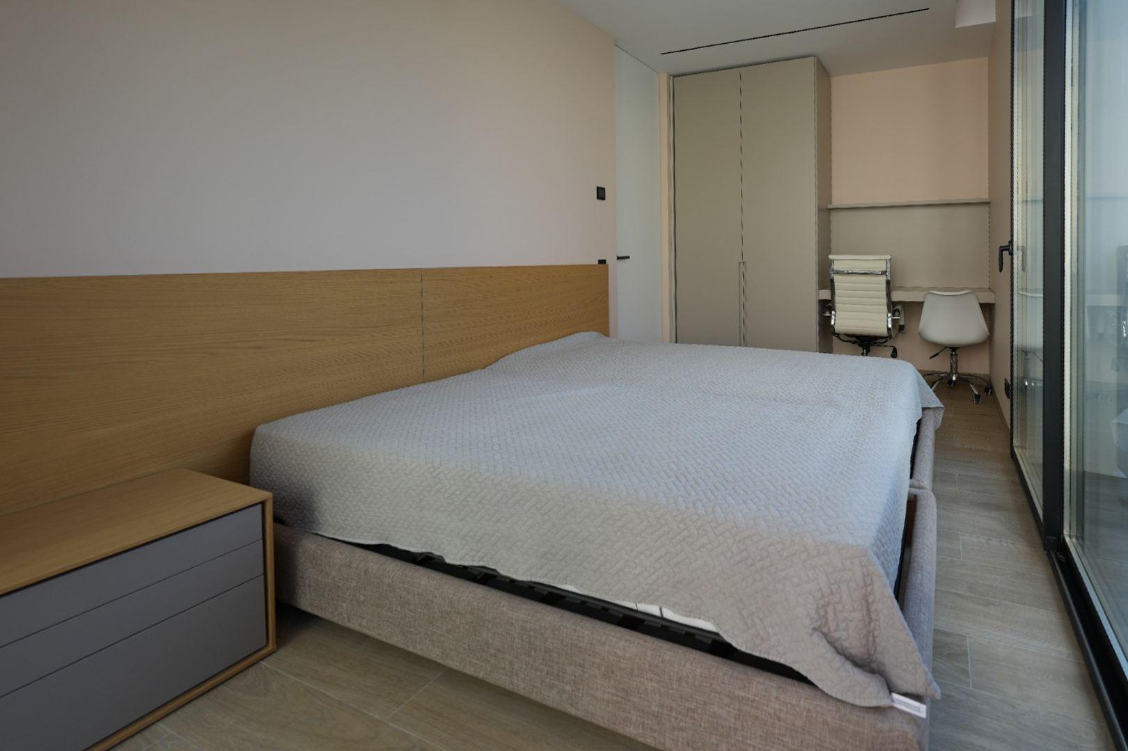 Modernes Schlafzimmer mit hellgrauem Polsterbett, Holzkopfteil und integriertem Nachttisch. Verfügt über Einbauschrank, doppelten Schreibtischbereich und große Glasfront.
