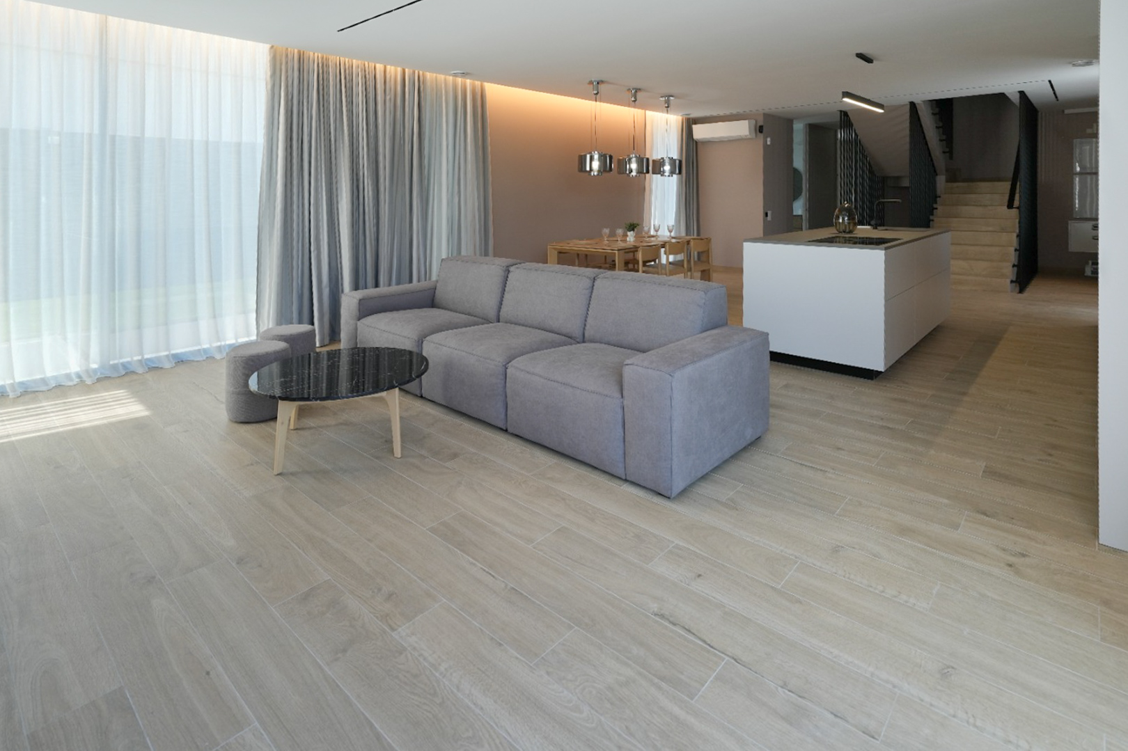 Offener Wohnbereich mit grauem Modulsofa, schwarzem Marmor-Couchtisch und holzoptik Fliesenboden. Große Fenster mit doppelten Vorhängen.