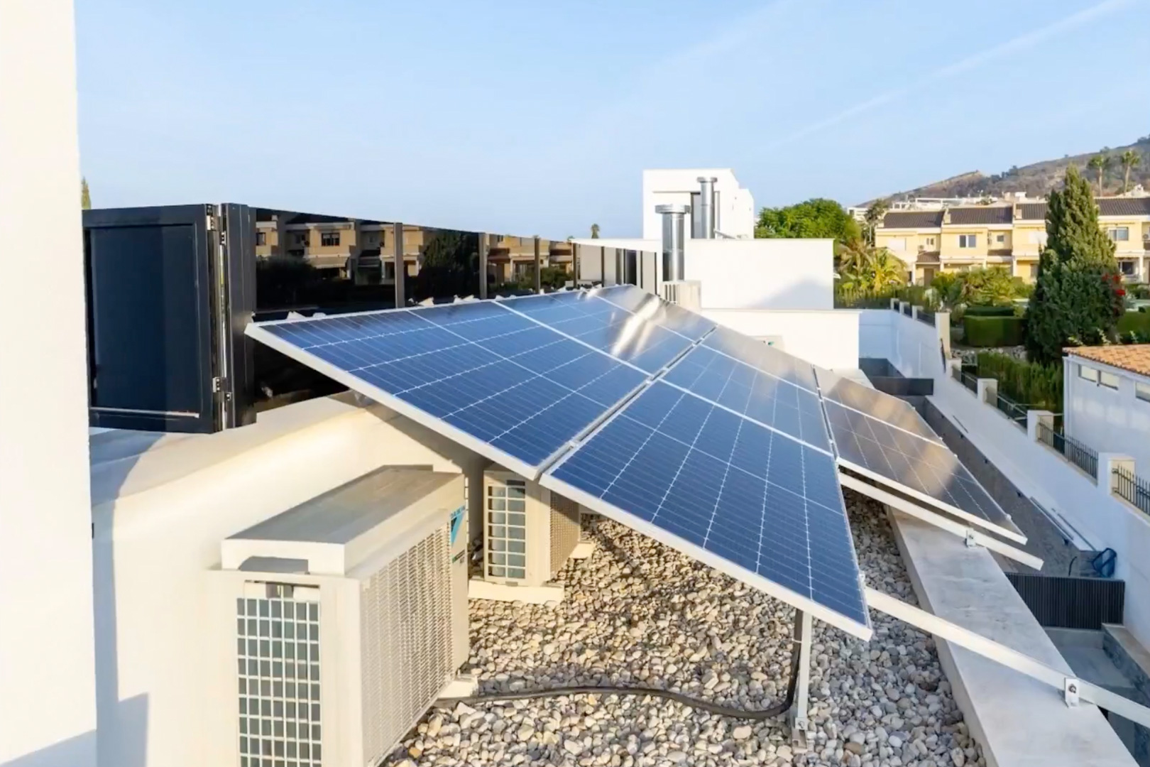 Umfassendes Photovoltaik-Solarsystem auf dem Dach. Klimaanlagen und eine helle Kiesfläche ergänzen diese hocheffiziente Installation.