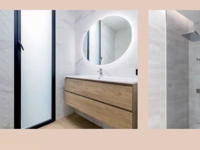 Modernes Badezimmer mit schwebendem Holzwaschtisch, beleuchtetem Ovalspiegel und Regendusche. Marmoroptik- und strukturierte Wandfliesen.