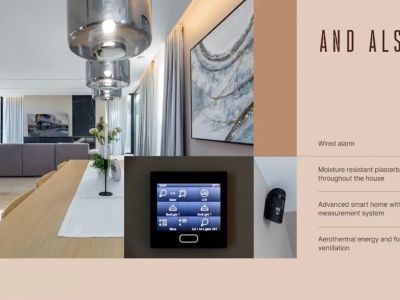 Offener Wohn-Essbereich mit Holztisch, Hängelampen und integriertem Smart-Home-Bedienfeld, ergänzt durch einen sichtbaren Sicherheitssensor.