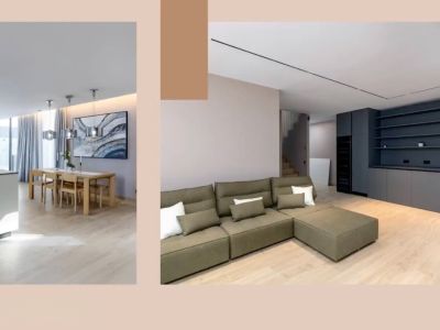 Offener Wohnbereich mit moderner Kücheninsel, Esstisch aus Holz und olivgrünem Ecksofa. Dunkelgraue Einbaumöbel und elegante Beleuchtung prägen das Design.