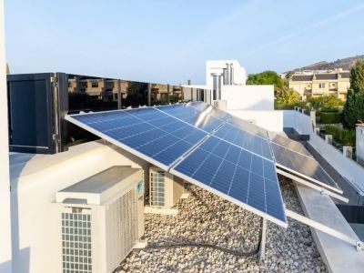 Umfassendes Photovoltaik-Solarsystem auf dem Dach. Klimaanlagen und eine helle Kiesfläche ergänzen diese hocheffiziente Installation.