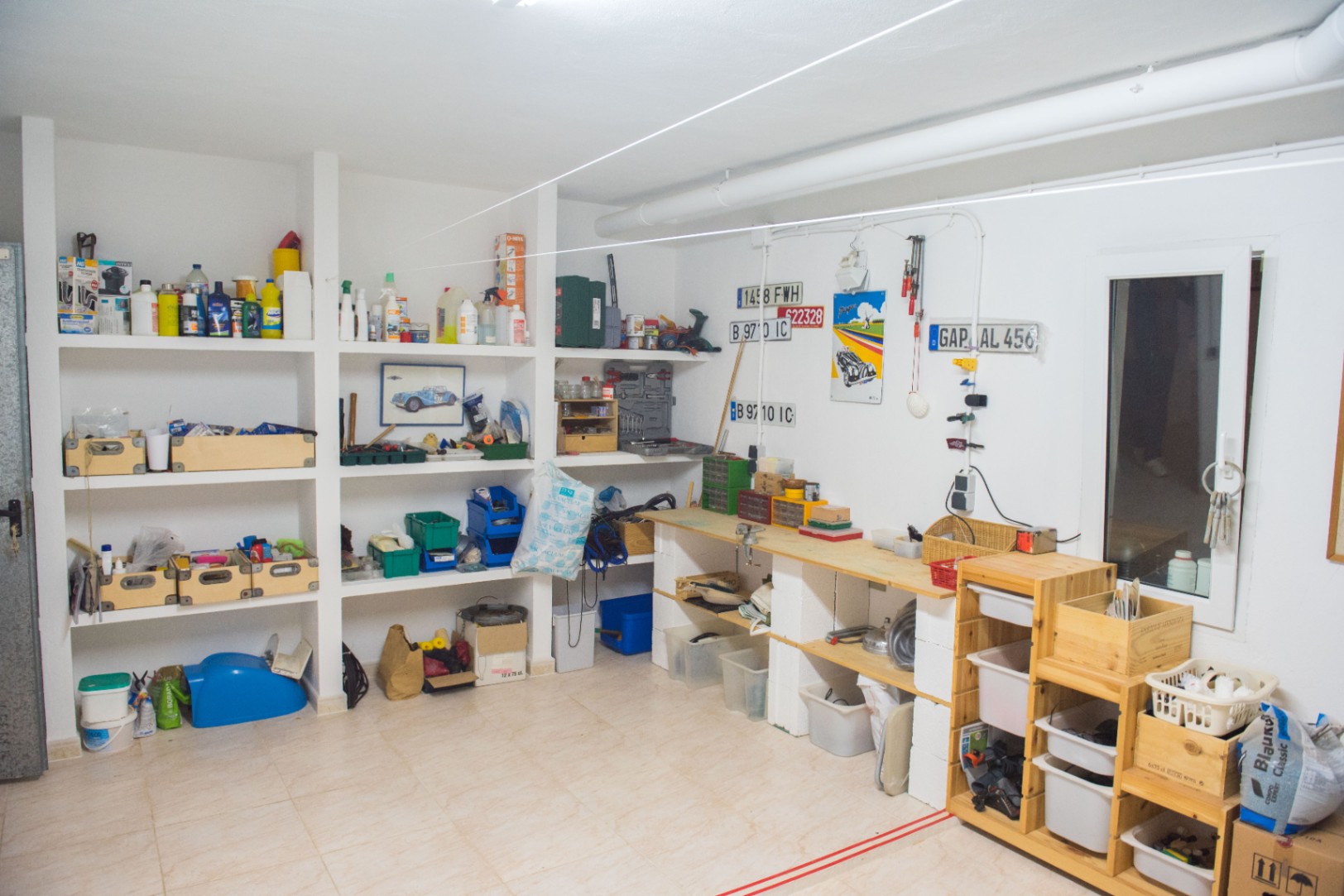 Geräumige Werkstatt und Lagerraum mit gemauerten Regalen, einer Holzwerkbank und Fliesenboden, ideal für Wartungsarbeiten und Hobbys.