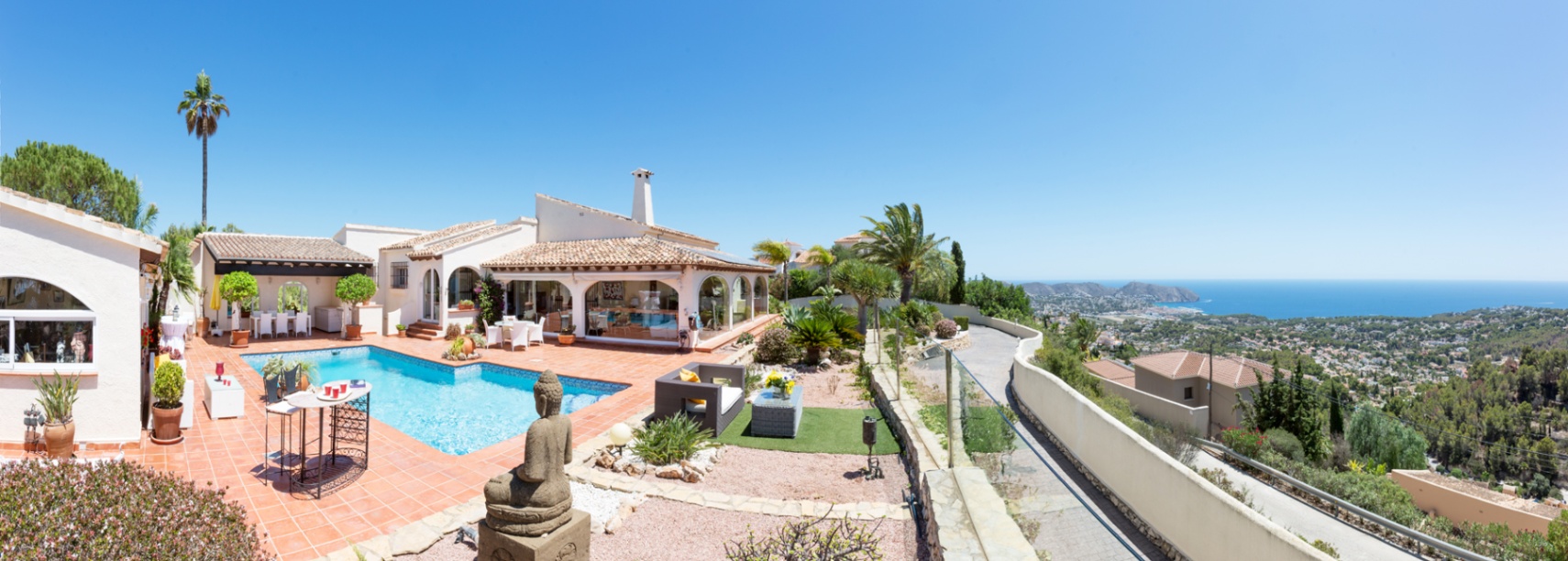 Panoramaterrasse mit Terrakottafliesen, privatem Pool und einer Buddha-Statue mit Blick auf das Mittelmeer und die Küstenlandschaft.