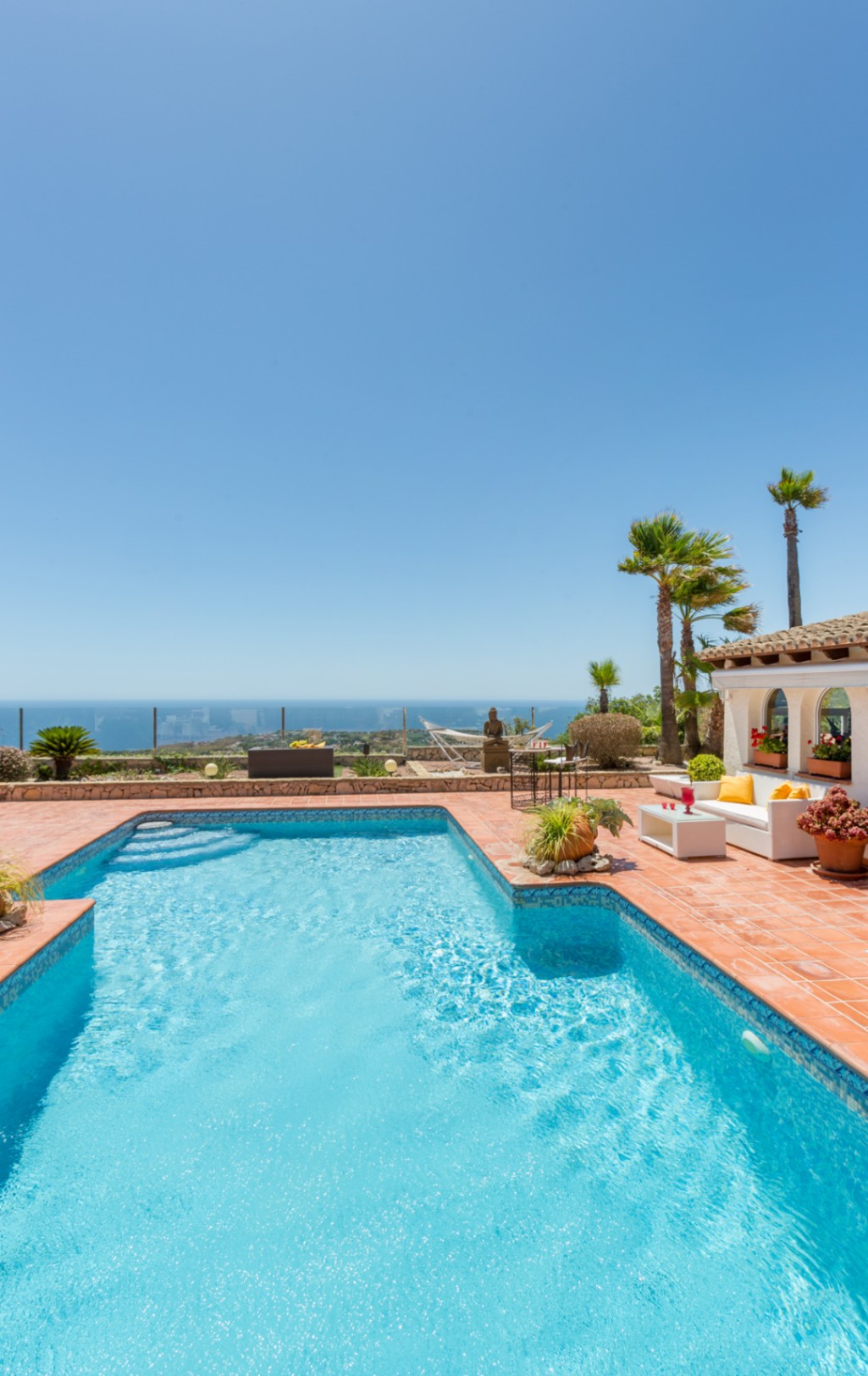 Pool mit blauen Mosaikfliesen und Terrakotta-Terrasse mit Lounge-Bereich, Palmen und Panoramablick auf das Mittelmeer in Cumbre del Sol.