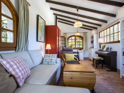 Helles Wohnzimmer mit Ledersofa, Holzbalken und Terrakottaböden, das Wohn- und Arbeitsbereiche kombiniert.