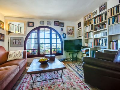 Wohnzimmer mit Bogenfenster und Aussicht, dekoriert mit gemustertem Teppich und einem Bücherregal voller Bücher.