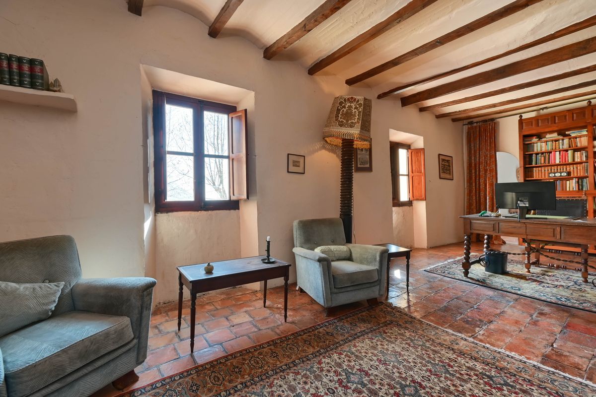 Arbeitszimmer mit sichtbaren Holzbalkendecken, Terrakottaböden und tiefen Fensternischen. Ausgestattet mit einem antiken Schreibtisch und Bücherregalen.