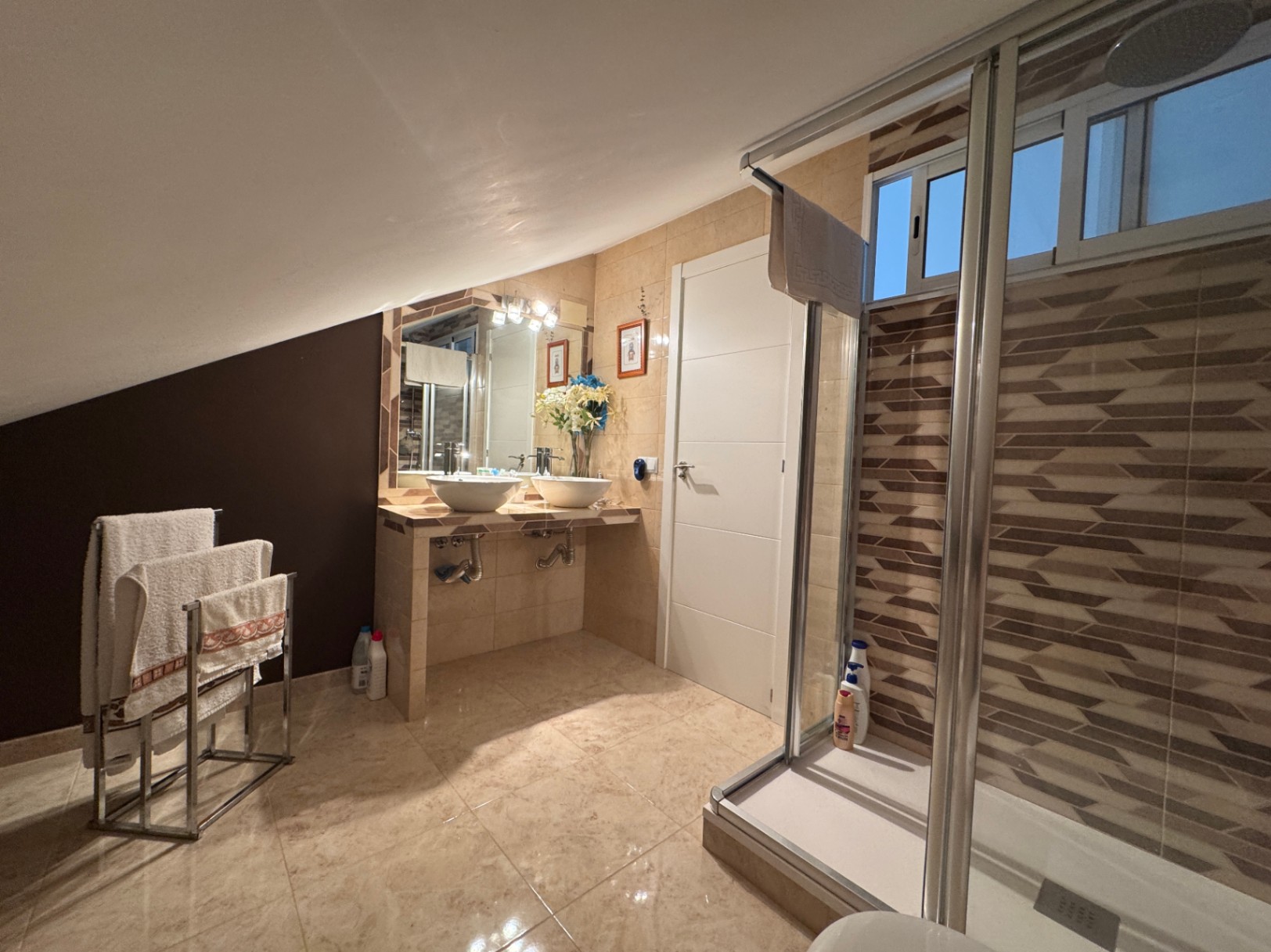 Badezimmer mit Doppelwaschbecken und Dusche mit Glasschiebetüren.