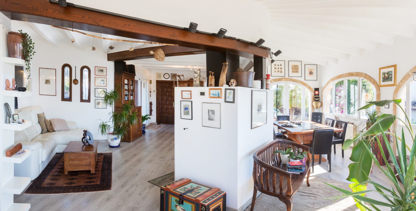 Offener Wohnbereich mit sichtbaren Holzbalken, gewölbter Decke und Rundbogenfenstern, die den Ess- und Wohnraum mit viel natürlichem Licht durchfluten.