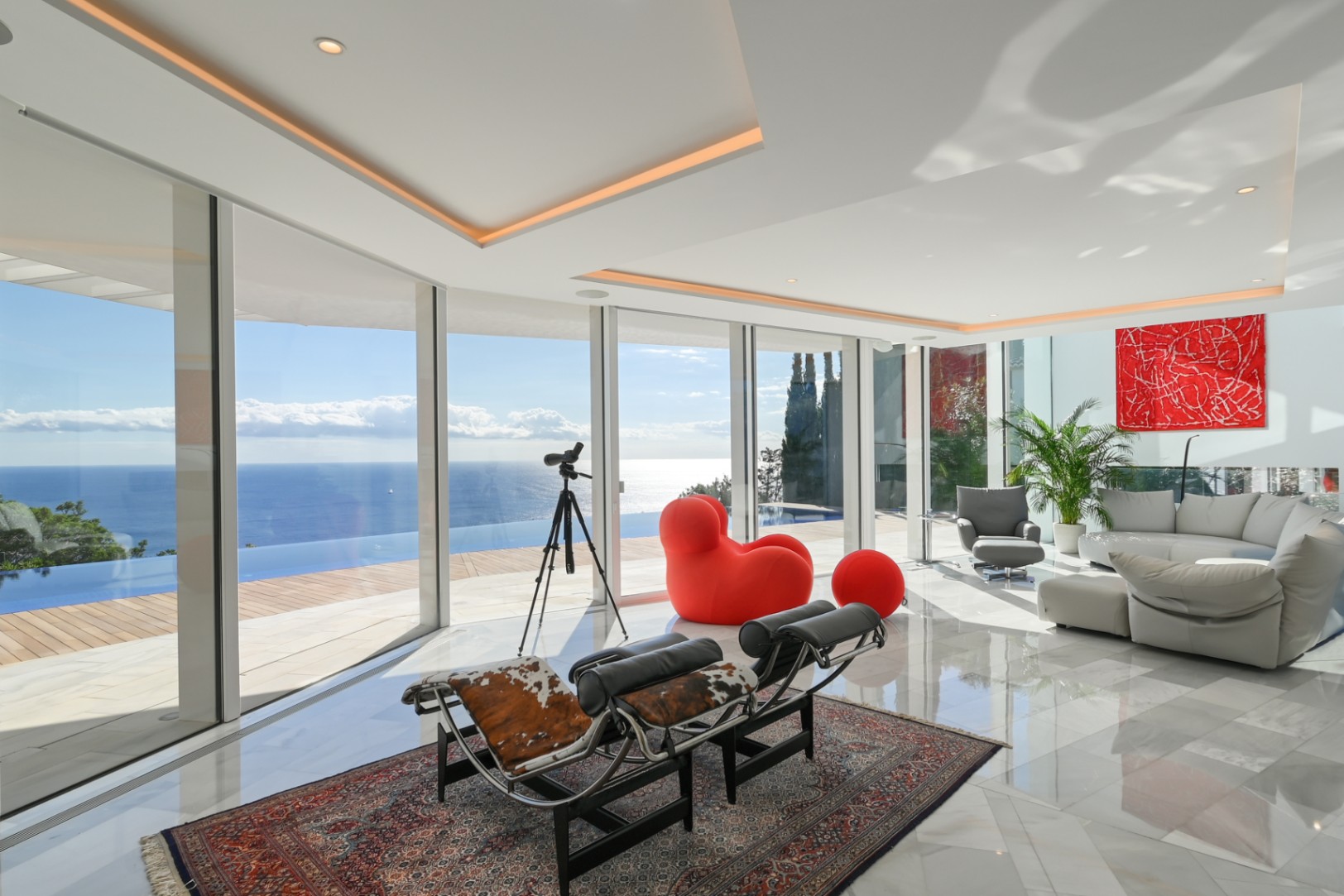 Heller Wohnbereich mit bodentiefen Glasfronten, Marmorboden und Designermöbeln mit Panoramablick auf den Infinity-Pool und das offene Meer.