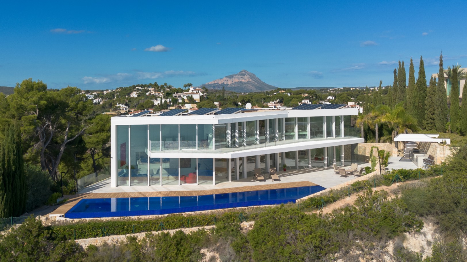 Moderne zweistöckige Villa mit bodentiefen Glasfronten, Infinity-Pool, Solarmodulen und Panoramablick auf den Berg Montgó.